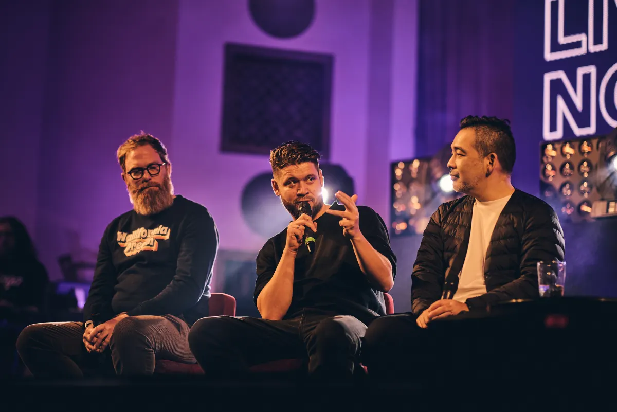 Three panellists on the purple-lit #MusicTech Slush 2024 stage, the one in the middle gesturing while speaking into a microphone